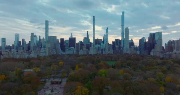 Wide panoramic view of skyscrapers surrounding Central park. Fly above autumn colour trees in park at dusk. Manhattan, New York City, USA — 图库视频影像