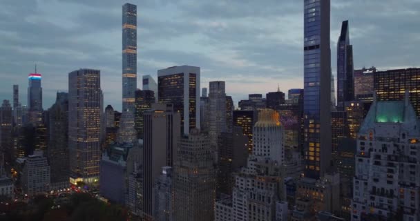 Внизу, в сутінках, хмарочоси. Передній політ над високими будівлями з освітленими вікнами. Мангеттен, Нью - Йорк, США — стокове відео