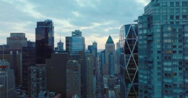 İleri doğru modern yüksek binalar boyunca uçar. Caddelerin yukarısındaki gökdelenlerin üst katları. Alacakaranlıkta gökyüzüne bak. Manhattan, New York City, ABD