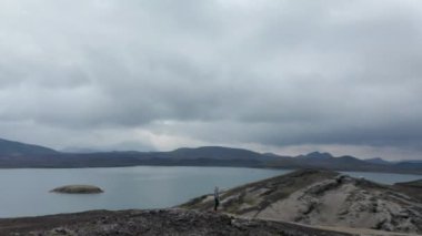 İnsansız hava aracı, insan kollarının etrafındaki yörüngeye bakıyor. İzlanda 'daki Skaftafell Ulusal Parkı' na hayranlık duyuyor. Dağın tepesinde maceraperest bir adam güzel manzaranın tadını çıkarıyor.