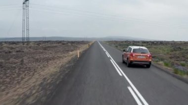 İzlanda 'da çevre yolunda giden arabayı takip eden kuş gözü drone. İzlanda 'nın kayalık dağları boyunca sonsuz yol boyunca hızla ilerleyen hava manzarası. Macera ve keşif kavramı