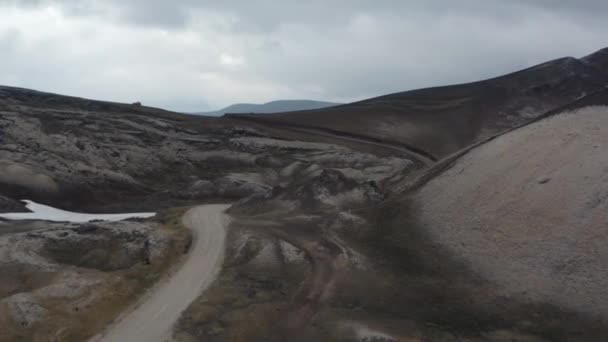 Drönare visa bil kör på grusväg i steniga ökenlandskap på Island. Prospektering och äventyr. Fåglar öga slingrande väg och surrealistiska landskap av islandshöglor — Stockvideo