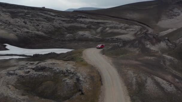 Widok z lotu ptaka 4x4 samochód jadący krętą drogą odkrywający dziką Islandię. Drone View offroad pojazdu podróży brud drogi w icelandyjskiej wsi. Przygoda i odkrywanie — Wideo stockowe
