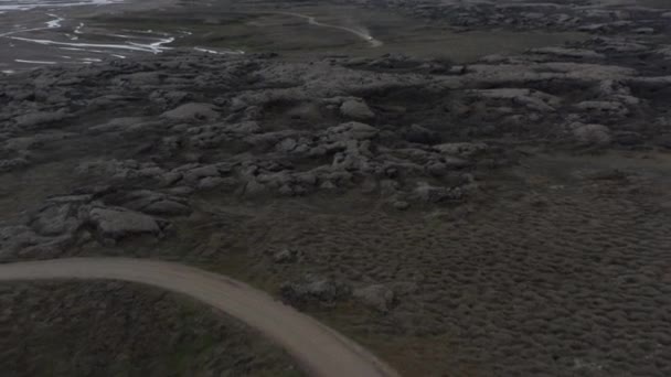 車の旅で山や未舗装の道路と素晴らしいアイスランドの風景の壮大な鳥の目のビュー。自然の美しさ。アイスランドの岩だらけの田舎の素晴らしい空の景色 — ストック動画