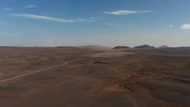 Pohled z ptačí perspektivy na dramatickou pouštní krajinu na Islandu. Vzdušný bezpilotní pohled na skalnaté a zaprášené panorama ostrohor se štěrkovou stezkou a horami v pozadí — Stock video