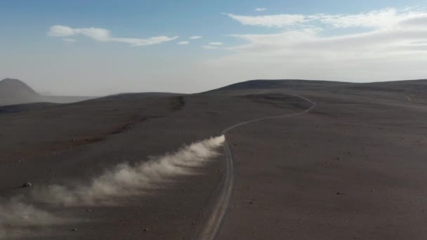 Pohled shora na majestátní islandskou krajinu s autem, které řídí skalní vrchoviny. Vysoký úhel pohledu auto jízdy rychlou dálnici rozdmýchání oblak prachu. Pojištění komerční — Stock video
