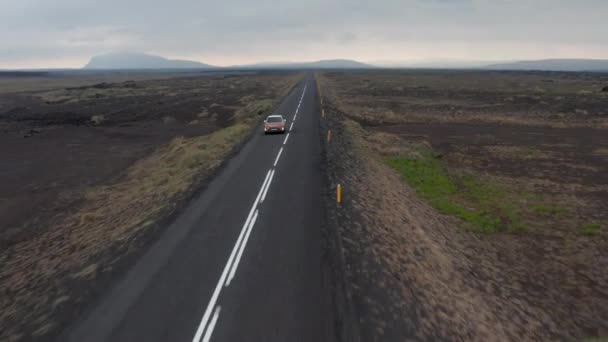 Drone view auto rijden langs de ringweg in IJsland, genieten van het wilde landschap. Bird eye view van majestueuze ijslandse hooglanden met auto snelrijdende snelweg. Handelsverzekeringsconcept — Stockvideo