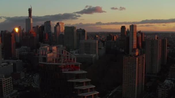 Fly above tall office or apartment buildings in city at dusk. Silhouettes of high rise towers against colourful twilight sky. Brooklyn, New York City, USA — Vídeo de Stock