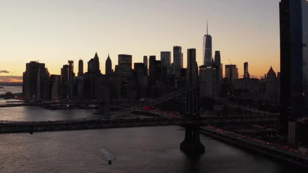 Breath taking romantic shot of downtown skyline at dusk. Silhouettes of modern skyscrapers against colourful sunset sky. Busy roads around river. Manhattan, New York City, USA — Stockvideo