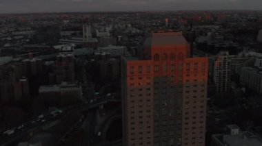 İleri doğru son güneş ışınlarıyla aydınlatılmış yüksek katlı apartman binasının üzerinden uçar. Alacakaranlıkta şehir mahallesinde. Brooklyn, New York City, ABD