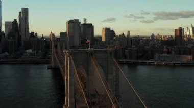 ABD Bayrağı gün batımında Brooklyn Köprüsü 'nün tepesinde dalgalanıyor. Şehir merkezindeki modern yüksek binaların inanılmaz manzarası. Manhattan, New York City, ABD