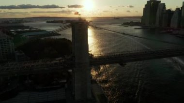 Brooklyn Köprüsü 'nün üzerinde renkli günbatımını yansıtan dalgalar. Manhattan, New York City, ABD