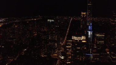 Gece şehrinin üzerinde uç. Şehir merkezindeki modern yüksek binalar. Yüksek binalardaki ışıklı pencereler. Manhattan, New York City, ABD