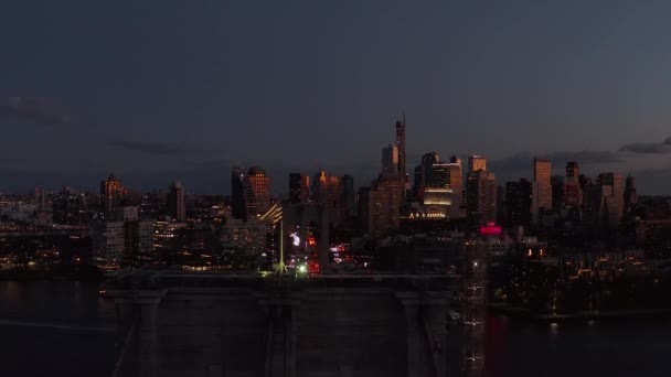 Forwards fly above American flag on top of Brooklyn Bridge. Heavy traffic in evening city. Panoramic view of high rise buildings at dusk. Brooklyn, New York City, USA — Vídeo de Stock