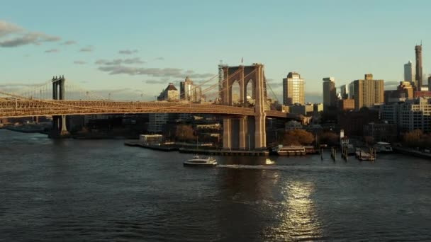 Utasszállító hajó halad el a Brooklyn híd alatt. Repülj a nyugodt folyó fölé. Városi szomszédság a háttérben. Brooklyn, New York City, Amerikai Egyesült Államok — Stock videók