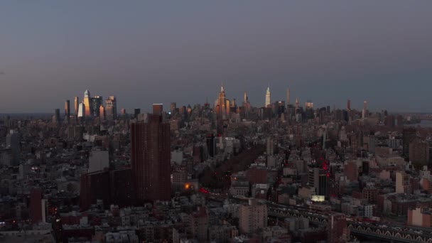 Flyg ovanför stadsdelen efter solnedgången. Moderna skyskrapor i centrum i fjärran reflekterande färgglada solnedgång. Manhattan, New York City, USA — Stockvideo