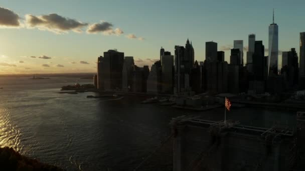 Respiración tomando imágenes aéreas del cielo colorido atardecer sobre el agua. Siluetas del Puente de Brooklyn y rascacielos del centro. Manhattan, Nueva York, Estados Unidos — Vídeo de stock