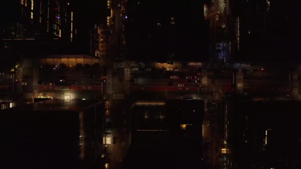 Aerial birds eye overhead top down panning view of busy multilane one way street at night. Vehicles driving between high rise buildings. Manhattan, New York City, USA — Stockvideo