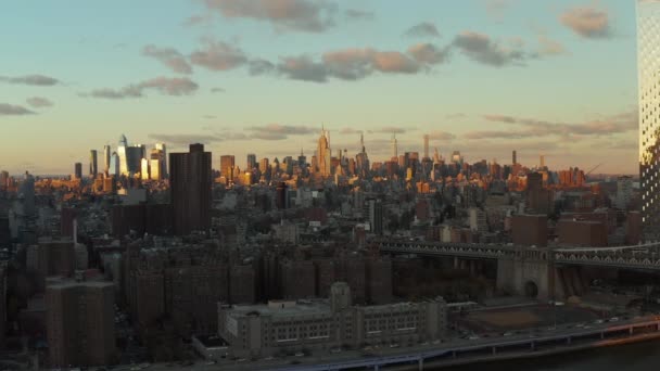 Sliding avslöja av vattnet och broar över floden. Stadsbild med höga skyskrapor upplysta av kvällssol. Manhattan, New York City, USA — Stockvideo