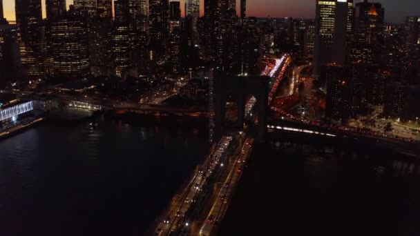 Година пік на Бруклінському мосту вночі. Підкресли до неба силуети хмарочосів у центрі міста. Мангеттен, Нью - Йорк, США — стокове відео