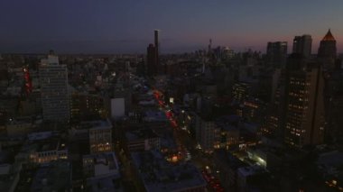 Akşamları şehrin alçalan görüntüsü. Şehirdeki işlek cadde ve alacakaranlık gökyüzüne karşı yüksek binaların siluetleri. Manhattan, New York City, ABD