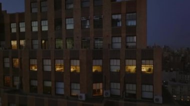Yüksek katlı ofis binası duvarı boyunca yükselen görüntüler. Gökdelenlerle gökdelenler son güneş ışınlarını yansıtıyor. Gün batımında şehir. Manhattan, New York City, ABD