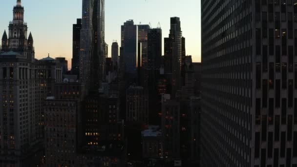 夕暮れ時に高層ビルの高層ビルの上昇映像。カラフルな夕日の空に対する高層オフィスビルのシルエット。米国ニューヨーク市マンハッタン — ストック動画