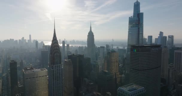 Dopředu létají nad budovami proti slunci. Mlhavý pohled na historické Chrysler a Empire State Building a moderní One Vanderbilt. Manhattan, New York City, USA — Stock video