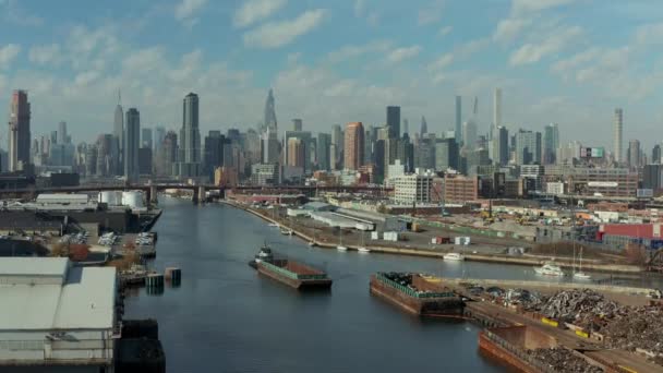 뉴타운 크릭에서 배가 바지선을 밀고 있는 장면입니다. 화물선 이 강둑에 정박 해 있었다. 고층 빌딩 이 있는 스카이라인. 미국 뉴욕 시 — 비디오
