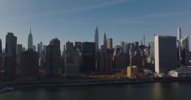 Framåt stiger flyga över vatten. Upptagen väg vid vattnet och höga byggnader i staden. Ikoniska skyskrapor. Manhattan, New York City, USA — Stockvideo