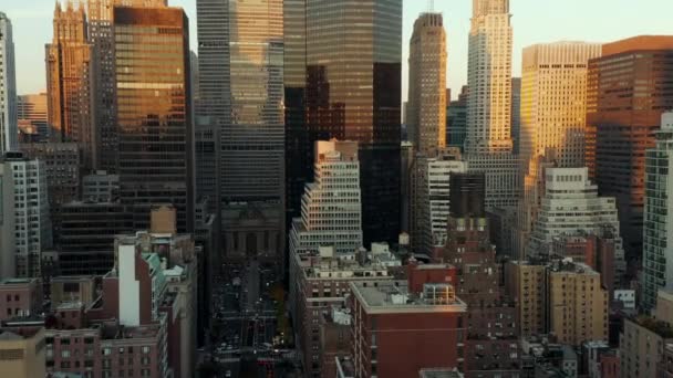 Avante sobrevoe edifícios no centro da cidade. Arranha-céus modernos com fachadas brilhantes que refletem o colorido céu do pôr-do-sol. Manhattan, Nova Iorque, EUA — Vídeo de Stock
