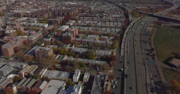 Řady obytných budov v městské čtvrti v blízkosti víceúrovňové dálniční komunikace. Letecký panoramatický záběr. Queens, New York City, USA — Stock video