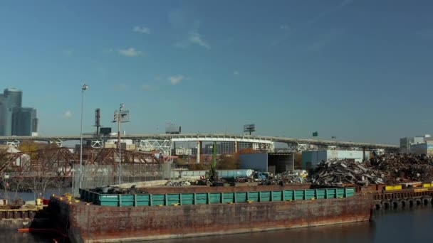 Vue aérienne de l'installation de recyclage. Pieux de ferraille sur le front de mer et barges pour le transport. Autoroute surélevée occupée en arrière-plan. New York, États-Unis — Video
