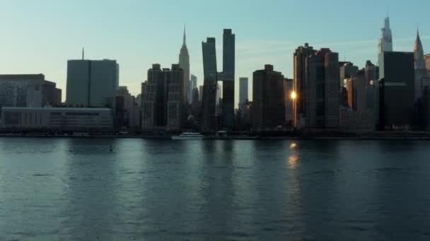 Fly over cruise boat floating on river. Silhouettes on high rise apartment buildings on waterfront. Manhattan, New York City, USA — 图库视频影像