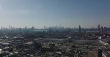 Endüstriyel alanın üzerinden geriye doğru uçun. Büyük, parlak çelik yumurta şekilli tanklar. Şehir merkezindeki gökdelenlerin ufuk çizgisi görünümü. Brooklyn, New York City, ABD