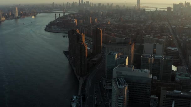 Воздушный панорамный снимок городского пейзажа против заходящего солнца. Занятая дорога на набережной. Манхэттен, Нью-Йорк, США — стоковое видео