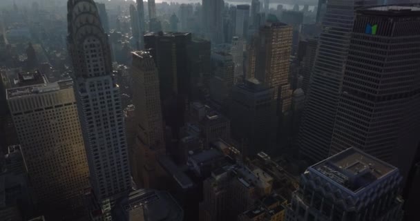 Hochwinkelblick auf Gebäude in der Innenstadt. Hochgeklappt offenbart sich ein majestätischer Büroturm. Trübe Sicht auf das Empire State Building gegen die Sonne. Manhattan, New York City, USA — Stockvideo