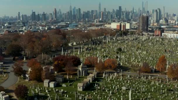 Aerial view of historic tombstones on Calvary Cemetery. Tilt up reveal of skyline with Manhattan skyscrapers. Queens, New York City, USA — Stockvideo