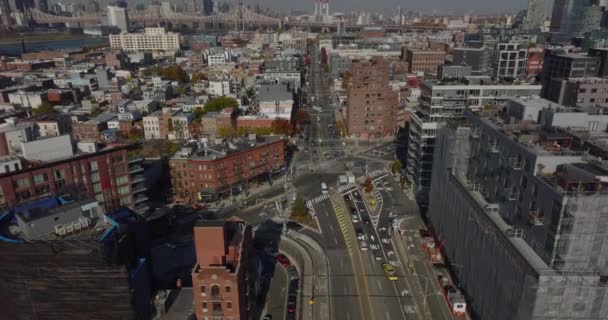 High angle view of cars driving through road intersection in urban borough. Tilt up reveal long bridge over river in distance. Queens, New York City, USA — Vídeo de Stock