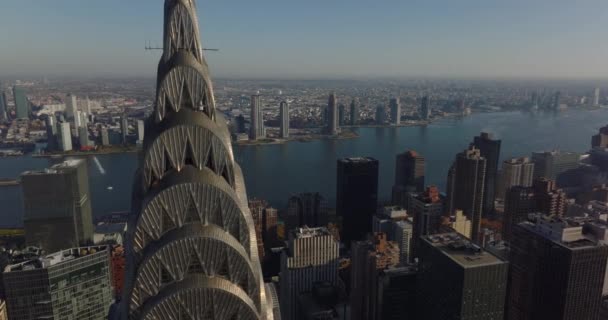 Fly around top of iconic Chrysler building. Revealing view of wide East river and boroughs on opposite bank. Manhattan, New York City, USA — Stock Video