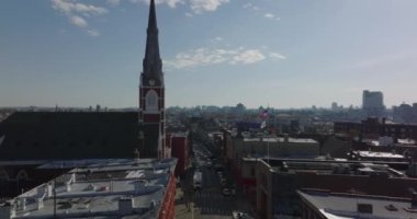 Forwardlar caddenin üzerinde uçar. Katolik kilisesinin yüksek kulesi çevresindeki gelişmelerin çok üstünde. Brooklyn, New York City, ABD