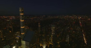 Şehirdeki aydınlanmış yüksek ofis kulelerinin görüntüleri iniyor. Arka planda gece manzarası. Manhattan, New York City, ABD