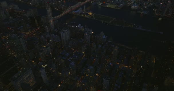 前方の夕方の都市の上を飛ぶ。照らさクイーンズボロ橋の高角度ビュー。米国ニューヨーク市マンハッタン — ストック動画