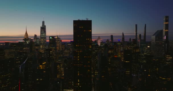 Slider van hoge gebouwen en straten in het centrum in de schemering. Verlichte wolkenkrabbers tegen de schemerlucht. Manhattan, New York City, Verenigde Staten — Stockvideo