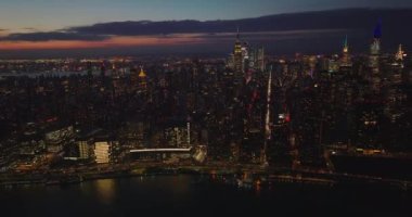 Aydınlatılmış gökdelenlerle akşam gökyüzü manzarası. Liman yolu üzerinde yoğun trafik var. Manhattan, New York City, ABD