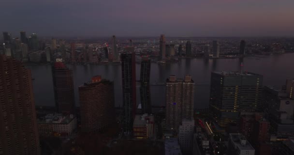 Forwards fly above evening city. Modern high rise apartment buildings on East River waterfront at dusk. Manhattan, New York City, USA — стокове відео