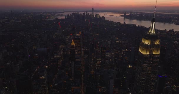 在帝国大厦明亮的上部和尖顶周围飞舞.黄昏时分，城市在五彩斑斓的天空中出现。美国，纽约市，曼哈顿 — 图库视频影像