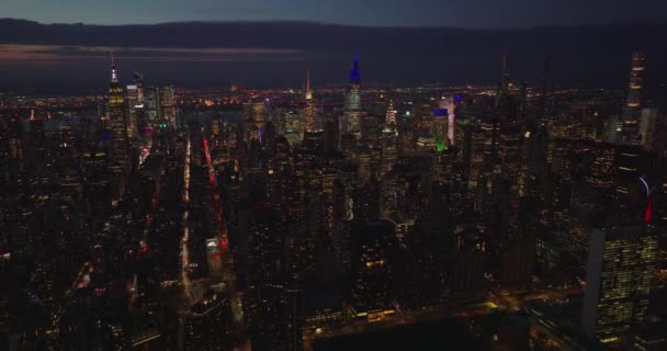 Vista aérea de rascacielos del centro de la ciudad por la noche. Revelar hacia atrás de la carretera concurrida en el paseo marítimo. Manhattan, Nueva York, Estados Unidos — Vídeo de stock