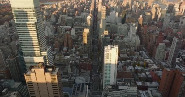 Tilt up mengungkapkan jalan lurus panjang melewati kota. Pemandangan kota di udara saat matahari terbenam. Manhattan, New York City, Amerika Serikat — Stok Video