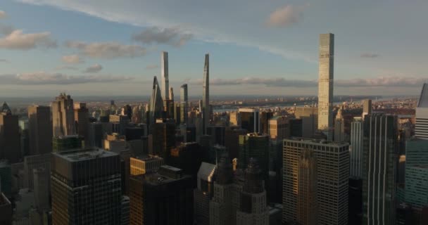Aerial ascending shot of modern office towers in city centre. Skyscrapers lit by setting sun. Manhattan, New York City, USA — стокове відео